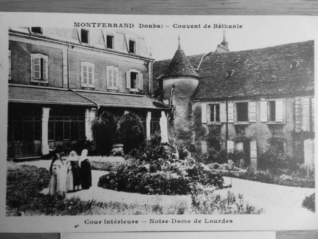 Carte postale ancienne du Couvent de Béthanie à Montferrand (Doubs), montrant la cour intérieure avec des religieuses et la statue de Notre-Dame de Lourdes.