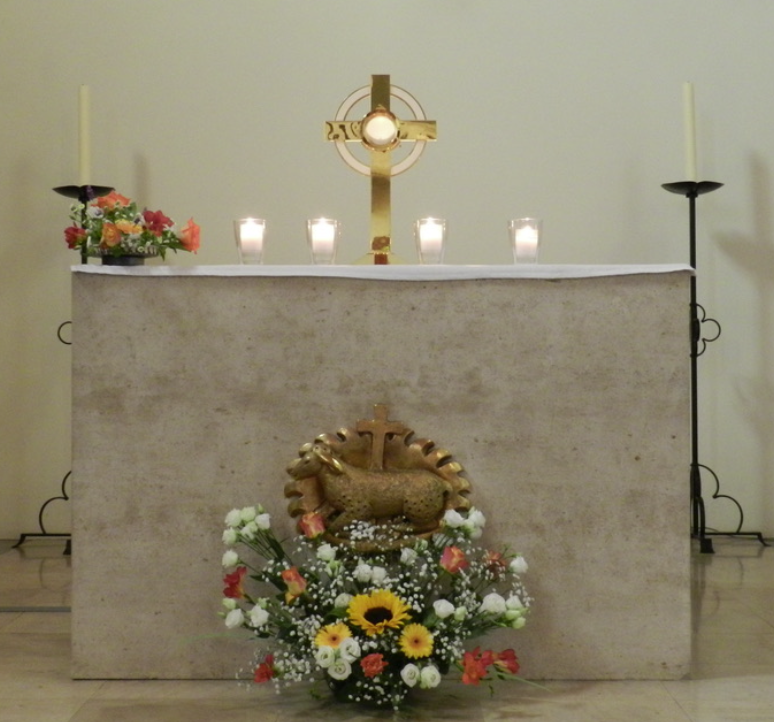 Autel d'église avec ostensoir doré, hostie et Agneau de Dieu, décoré de bougies et fleurs